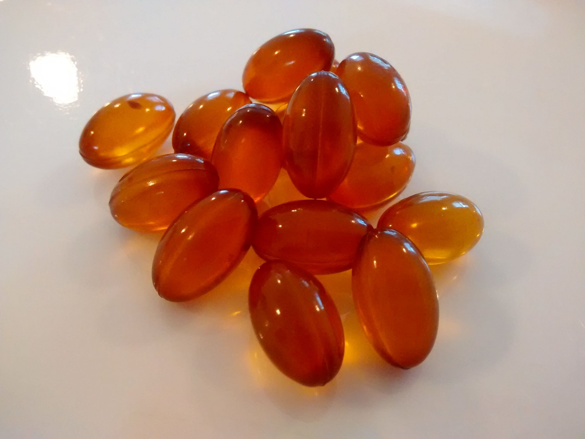 A pile of amber softgel supplement capsules photographed close up.