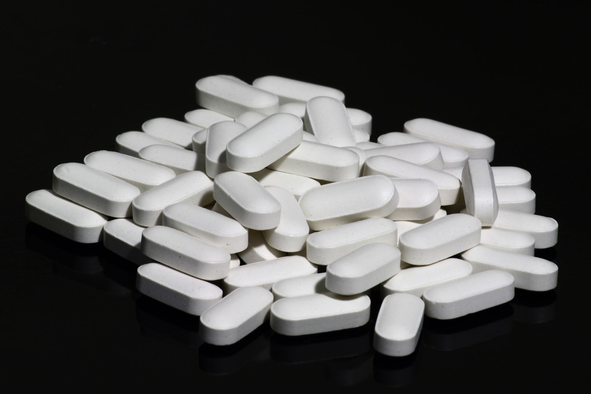 White calcium supplement tablets with added vitamin D, piled together.