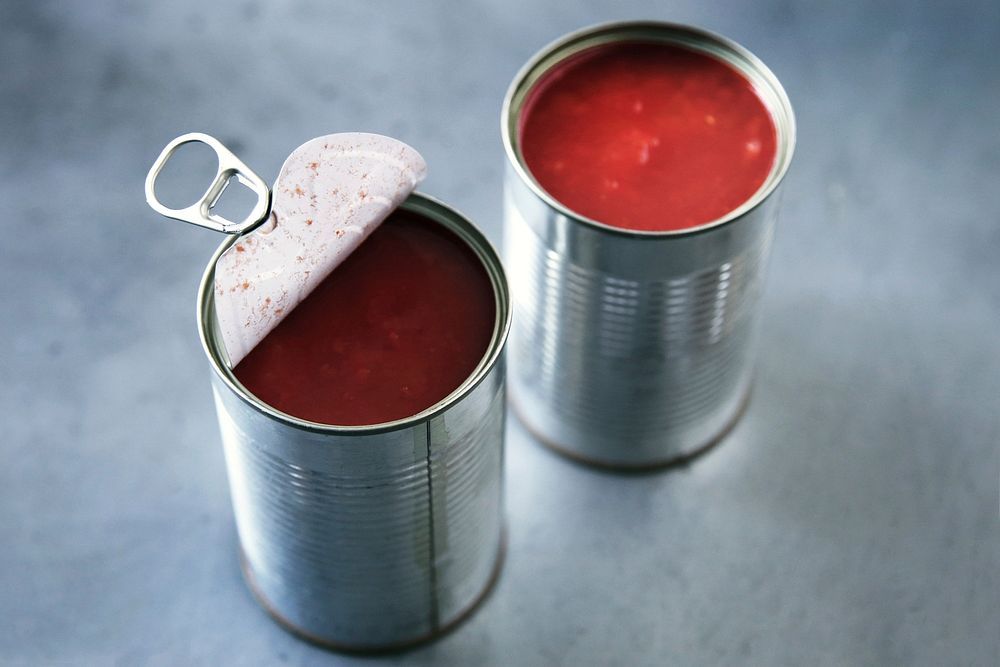 Δύο ανοιχτές μεταλλικές κονσέρβες με ντομάτα.